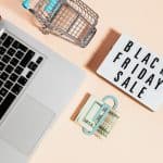 What Do Tech Gurus Wear? 8 Top View of Silver Macbook Beside a Shopping Cart and Black Friday Sale Signage