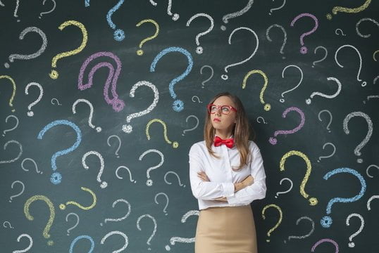 Businesswoman and question marks on blackboard