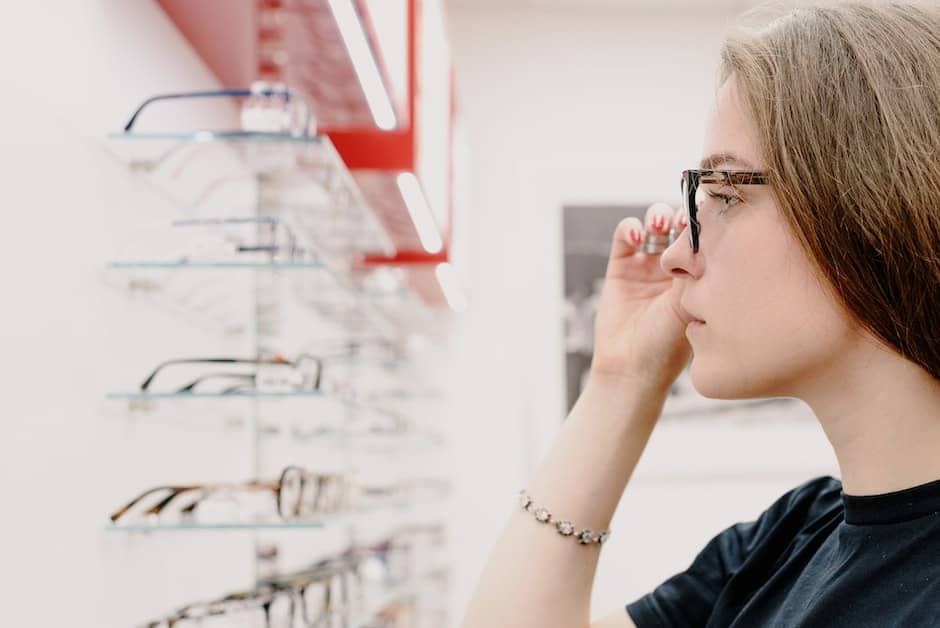 Side view of crop concentrated female customer putting on eyeglasses for improving eyesight while ch