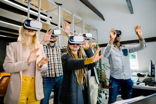 Team of five young multiethnic developers in casual wear working with virtual reality glasses during