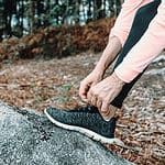 close up of a hiker adjusting there shoes on a big rick